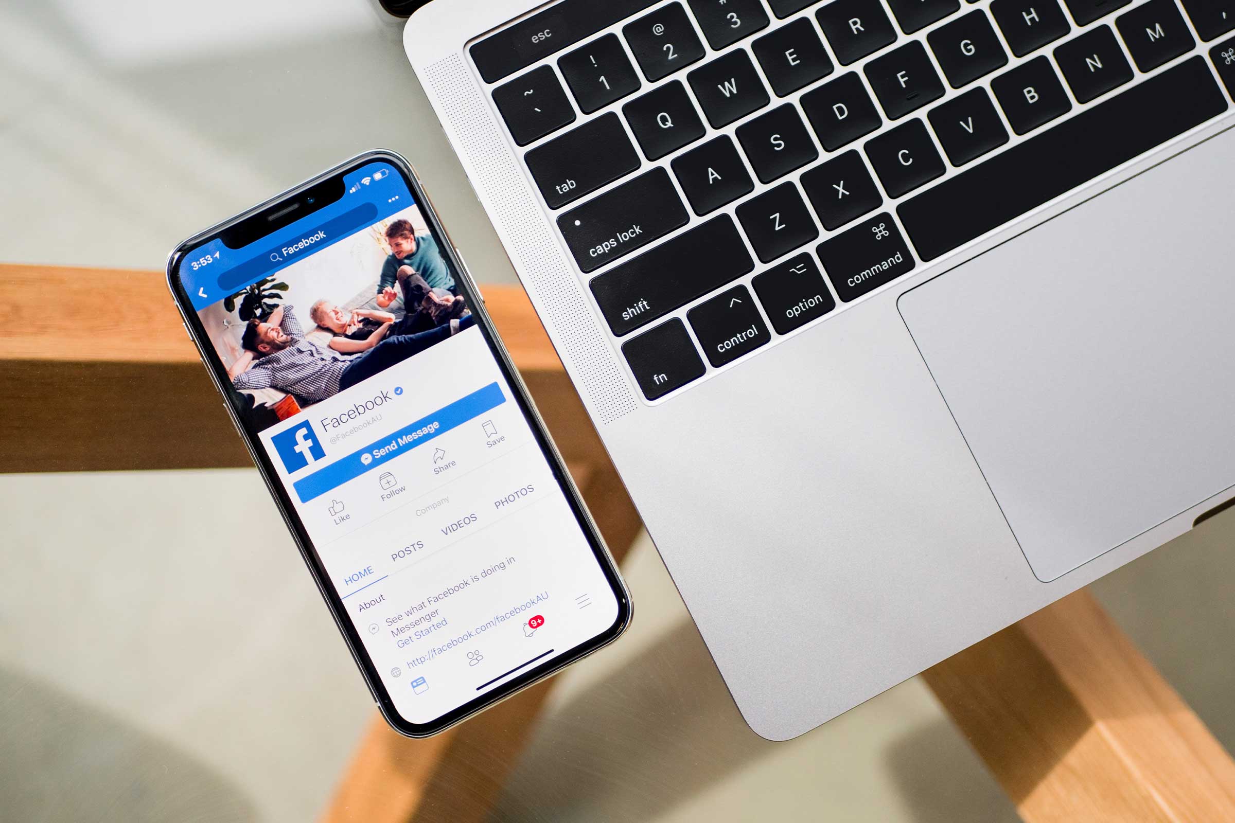 phone next to a laptop with a Facebook profile on the screen